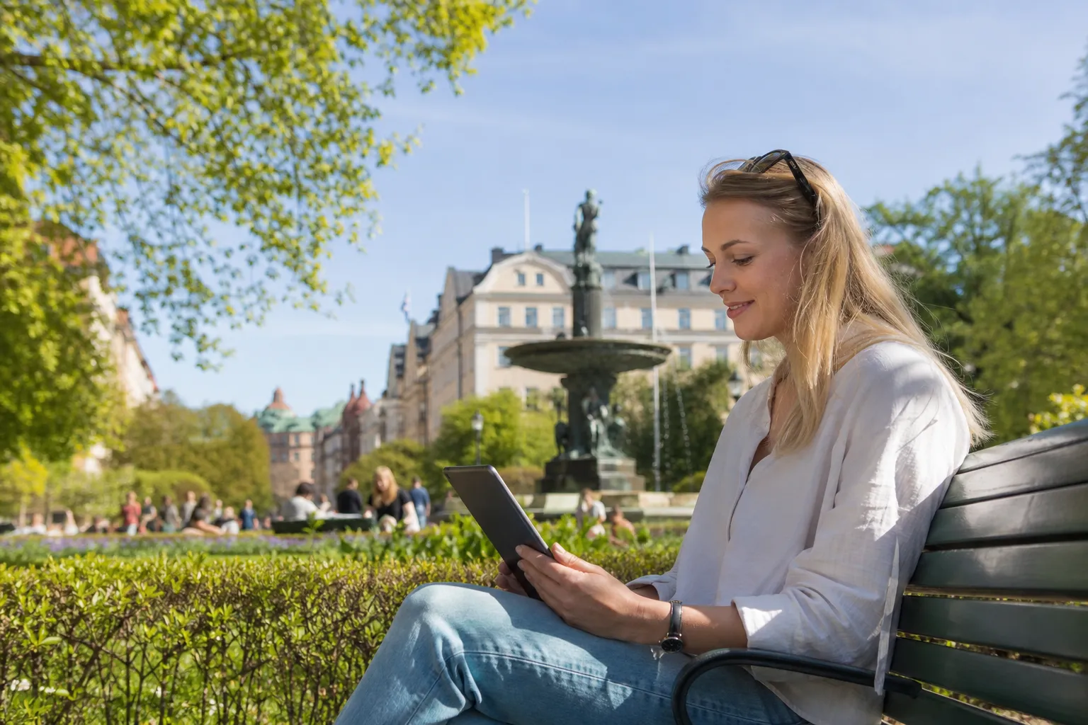 Person med surfplatta och mobilt bredband i stadspark